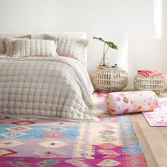 a bedroom with a bed, rugs and two planters on the floor next to it