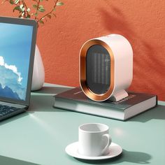 a laptop computer sitting on top of a desk next to a cup and saucer