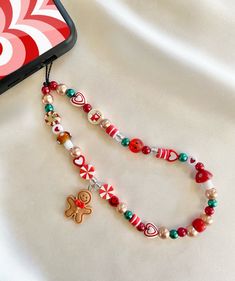 ♡ Jolly Gingerbread Christmas Phone Charm Strap ♡ Approximately 8 inches in length from top of cord to bottom of beads ♡Made with: * black waxed cord  * acrylic beads * plastic beads * clay beads ♡ Beads and bead colors may vary but will look very similar to the phone charm pictured ♡ Please contact me if you have any questions or any bead color preferences DISCLAIMER:  * All of our phone charms are not intended for small children  * Beads are a choking hazard for children * BestieBeadz assumes How To Phone Charm, Christmas Phone Charm Ideas, Christmas Charms Diy, Christmas Phone Charm, Clay Bead Phone Charm Ideas, Christmas Phone Ideas, Bead Crafts For Adults, Clay Bead Phone Charm, Christmas Beaded Jewelry