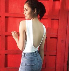 a woman standing in front of a red wall with her back turned to the camera