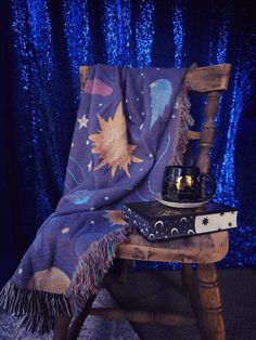 a wooden chair with a blanket on top of it and a tea pot sitting on the seat