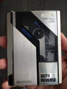 a person holding a silver and black electronic device in their hand with the words awa on it