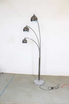 a lamp that is sitting on the ground in front of a wall with three lights attached to it