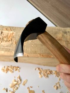 a person is holding a hammer in their right hand and wood shavings on the other