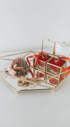 a glass tray with red candles and flowers in it sitting on a white counter top