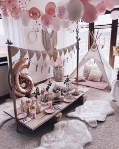 a room filled with lots of pink and white balloons hanging from the ceiling over a table