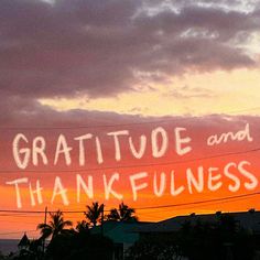 graffiti written on the side of a telephone pole in front of an orange and pink sky