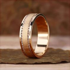 a wedding ring with two rows of diamonds on the inside and outside, sitting on top of a piece of wood