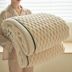 a woman holding a large white blanket in front of a window