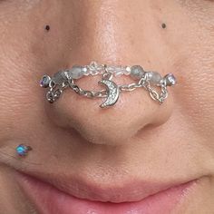 a close up of a woman's nose with a chain around her nose ring