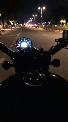 a motorcycle is parked on the side of the road at night with its lights on