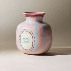 a pink and blue striped vase sitting on top of a table