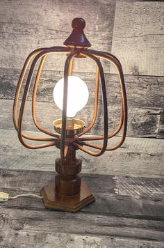 an old fashioned table lamp on a wooden surface with a light bulb in the middle