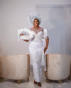 a woman in a white dress and headdress standing next to two couches