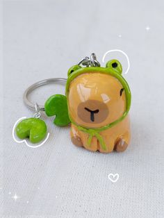 a keychain shaped like a bear with a green hat on it's head