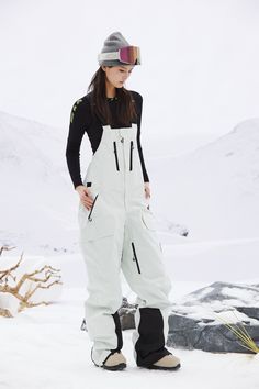 a woman standing in the snow with skis on her feet and one hand on her hip