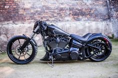 a black motorcycle parked in front of a brick wall