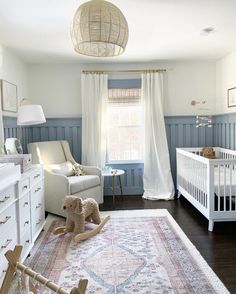 a baby's room with a white crib, rocking chair and large rug