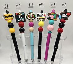 several pens are lined up in a clear holder with magnets on them and one has a name tag attached to it