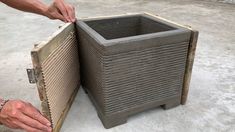 a man is holding the bottom part of a large square planter in his hands