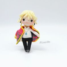 a crocheted doll wearing a white shirt and black pants, holding a yellow jacket