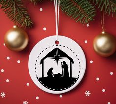 a christmas ornament with a nativity scene hanging from the tree on a red background