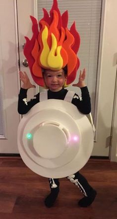 a young boy dressed up as a fireman holding a frisbee