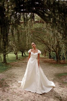 a woman in a wedding dress standing under trees