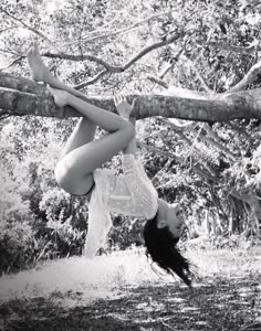 a woman hanging upside down on a tree branch