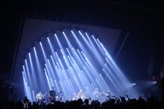 a group of people that are on stage with some lights in the dark behind them