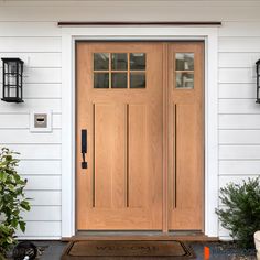 the front door of a white house with wooden doors