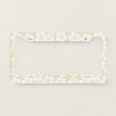 a white flowered license plate frame on a light colored background with the word,