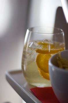 two glasses of wine with orange slices in them on a tray next to a pitcher