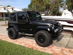 a black jeep is parked next to a boat