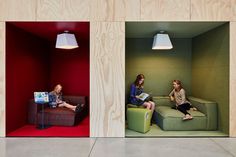 two people sitting on couches in a room with red walls and wood paneling