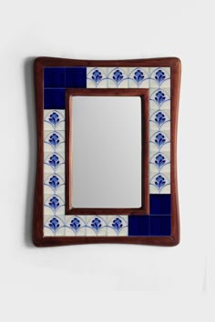 a blue and white tile mirror mounted on a wall next to a wooden framed mirror