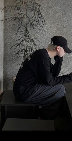 a man sitting on top of a black table next to a plant