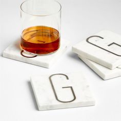 marble coasters with the letter g on them and a glass of whiskey in front