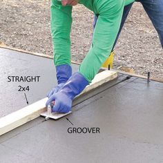 a man in blue gloves and green pants working on a piece of wood