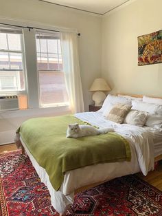 a cat is sitting on the edge of a bed in a room with hardwood floors