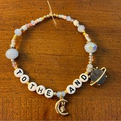 a beaded bracelet with the word to the land written on it and a crescent charm