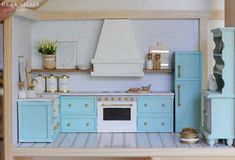 a doll house kitchen with blue cabinets and white counter tops, including a stove top oven