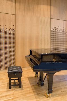 a grand piano and stool in a room with wood paneling