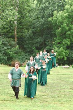 a group of people dressed in green standing on top of a grass covered field next to trees