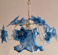 a blue glass chandelier with flowers hanging from it's sides and two lights on each side