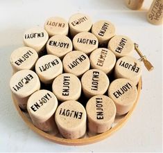 several wine corks with words written on them in a wooden bowl next to two bottles