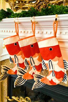 three christmas stockings hanging from a fireplace mantel decorated with fish and striped red and white fabric