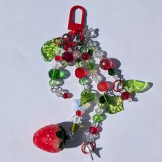 a red keychain with beads and charms attached to it on a white surface