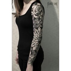 a woman with black and white tattoos on her arm is standing in front of a wall