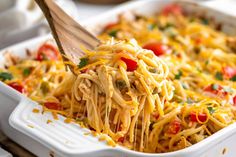 a casserole dish with noodles and vegetables being lifted from the casserole